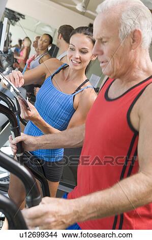 Picture - Personal Trainer Instructing Man On Treadmill. Fotosearch