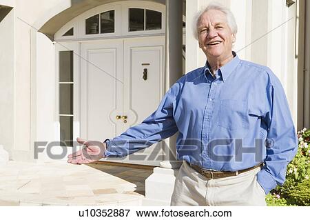 Stock Photo - Senior man standing outside his home. Fotosearch