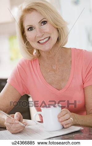 Woman in kitchen with coffee and newspaper smiling View Large Photo Image Stock Photography - Woman in kitchen with coffee and newspaper smiling. Fotosearch