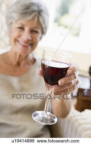 Woman in living room with glass of wine smiling View Large Photo Image Stock Photo - Woman in living room with glass of wine smiling. Fotosearch