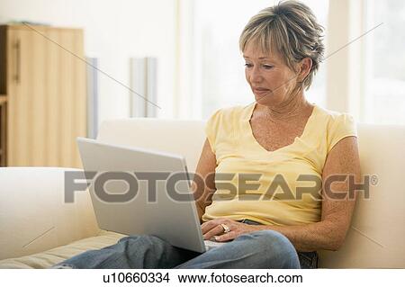 Woman in living room with laptop smiling View Large Photo Image Picture - Woman in living room with laptop smiling. Fotosearch