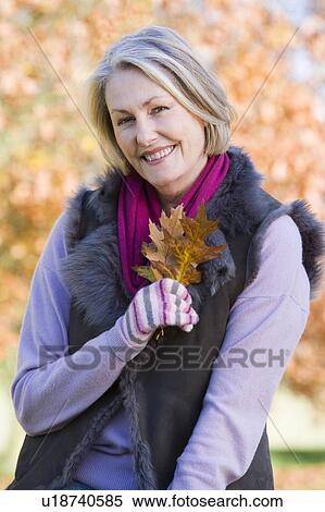 Woman outdoors at park holding leaves in hand smiling (selective focus) View Large Photo Image Stock Photography - Woman outdoors at park holding leaves in hand smiling (selective focus). Fotosearch