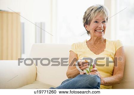 Woman relaxing in living room with coffee smiling View Large Photo Image Stock Image - Woman relaxing in living room with coffee smiling. Fotosearch