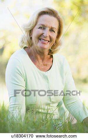 Woman sitting outdoors smiling View Large Photo Image Stock Image - Woman sitting outdoors smiling. Fotosearch