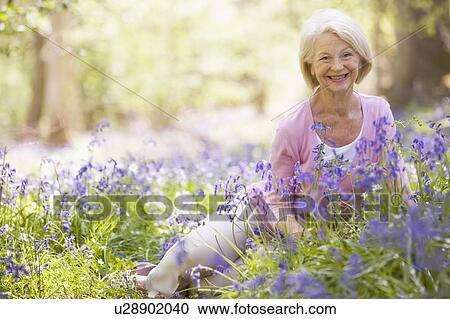 Woman sitting outdoors with flowers smiling View Large Photo Image Stock Image - Woman sitting outdoors with flowers smiling. Fotosearch