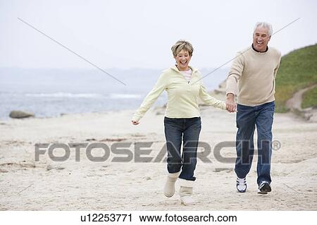 Couple at the beach holding hands and smiling View Large Photo Image Stock Image - Couple at the beach holding hands and smiling. Fotosearch