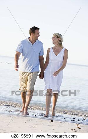 Couple at the beach holding hands and smiling View Large Photo Image Stock Image - Couple at the beach holding hands and smiling. Fotosearch