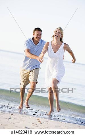 Couple at the beach playing and smiling View Large Photo Image Stock Photo - Couple at the beach playing and smiling. Fotosearch