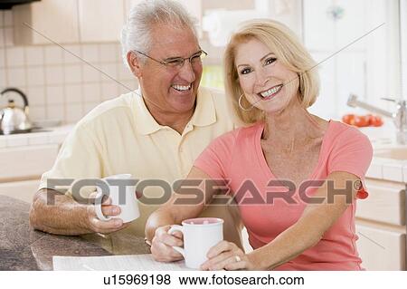 Stock Photo - Couple in kitchen with coffee smiling. Fotosearch