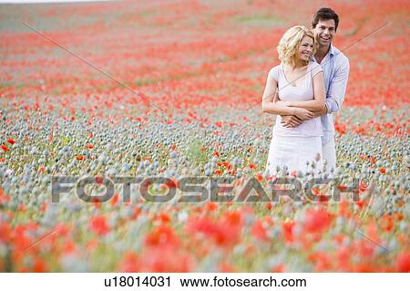 Couple in poppy field embracing and smiling View Large Photo Image Stock Image - Couple in poppy field embracing and smiling. Fotosearch