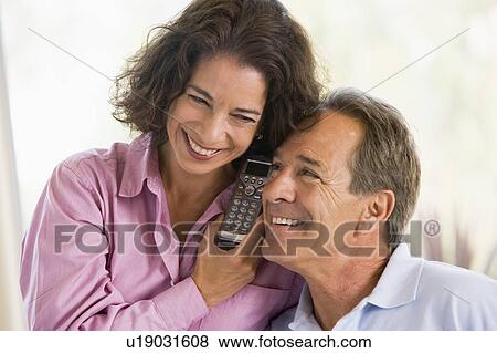 Stock Photo - Couple indoors using telephone smiling. Fotosearch