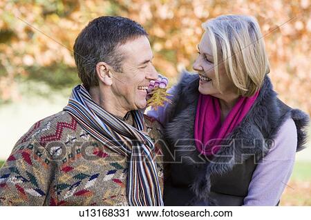 Stock Image - Couple outdoors in park bonding and smiling (selective focus). Fotosearch