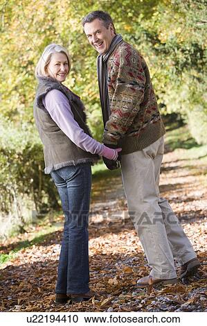 Couple outdoors on path in park holding hands and smiling (selective focus) View Large Photo Image Stock Image - Couple outdoors on path in park holding hands and smiling (selective focus). Fotosearch