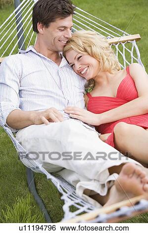 Stock Photograph - Couple relaxing in hammock smiling. Fotosearch