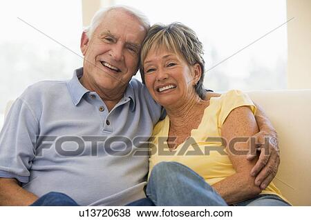 Stock Photo - Couple relaxing in living room smiling. Fotosearch