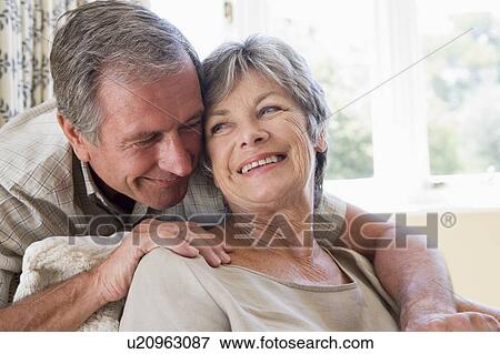 Stock Photo - Couple relaxing in living room smiling. Fotosearch