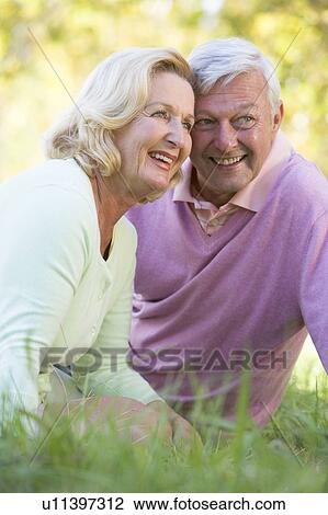 Couple relaxing in park smiling View Large Photo Image Stock Image - Couple relaxing in park smiling. Fotosearch