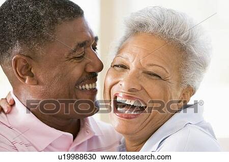 Stock Image - Couple relaxing indoors laughing. Fotosearch