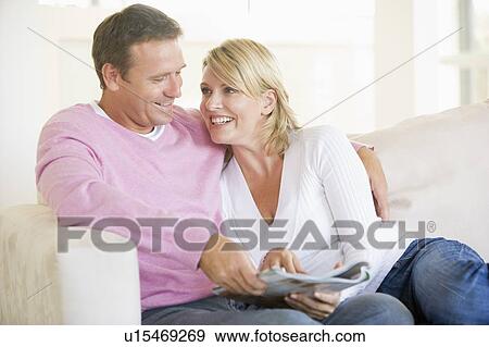 Couple relaxing with a magazine and smiling View Large Photo Image Stock Photo - Couple relaxing with a magazine and smiling. Fotosearch