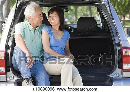 Stock Photograph - Couple sitting in back of van smiling. Fotosearch