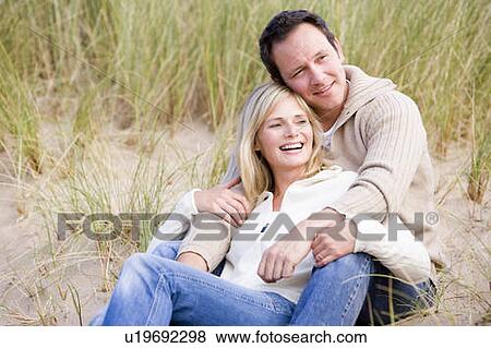 Stock Photo - Couple sitting on beach smiling. Fotosearch