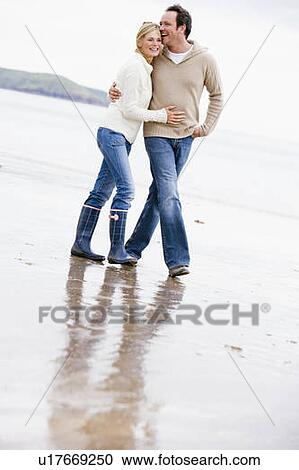 Couple walking on beach arm in arm smiling View Large Photo Image Stock Image - Couple walking on beach arm in arm smiling. Fotosearch
