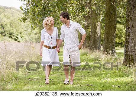 Stock Photography - Couple walking on path holding hands smiling. Fotosearch