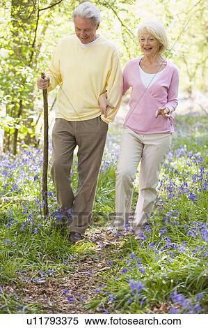 Stock Photography - Couple walking outdoors with walking stick smiling. Fotosearch