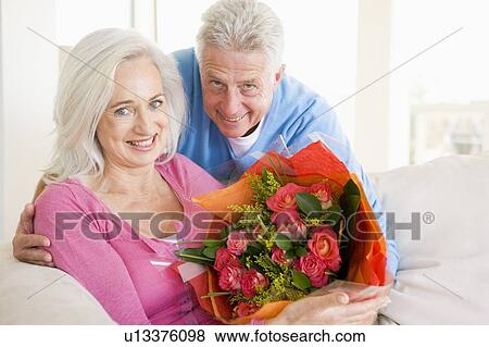 Stock Photo - Husband and wife holding flowers and smiling. Fotosearch