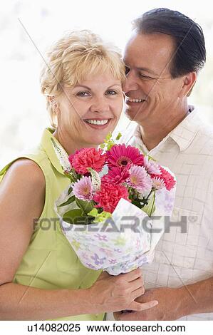 Stock Photography - Husband and wife holding flowers and smiling. Fotosearch