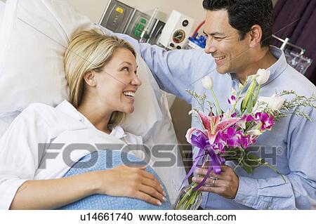 Stock Image - Man Giving His Pregnant Wife Flowers. Fotosearch