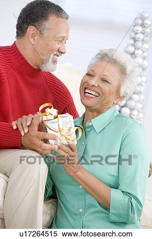 Stock Photography - Senior Couple Exchanging A Christmas Gift. Fotosearch