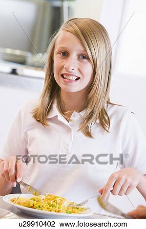 Stock Image - Student in cafeteria eating lunch (selective focus). Fotosearch