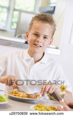 Stock Photo - Student in cafeteria eating lunch (selective focus). Fotosearch