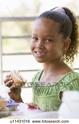 Stock Photograph - Student outdoors eating lunch (selective focus). Fotosearch