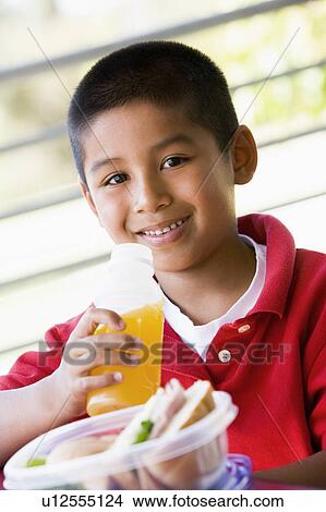 Student outdoors with lunch drinking juice (selective focus) View Large Photo Image Picture - Student outdoors with lunch drinking juice (selective focus). Fotosearch