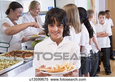 Stock Photography - Students in cafeteria line with one holding his unhealthy meal and looking at camera (depth of field). Fotosearch