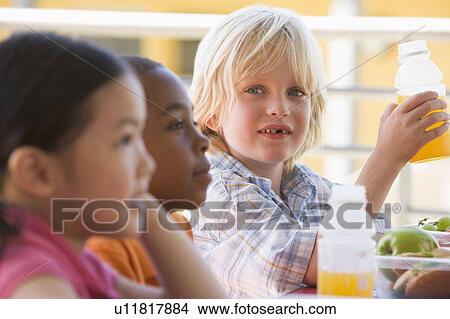 Picture - Students outdoors eating lunch (selective focus). Fotosearch
