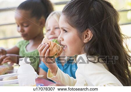 Stock Photo - Students outdoors eating lunch (selective focus). Fotosearch