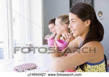 Three young women having a cold drink in a cafeteria View Large Photo Image Stock Photo - Three young women having a cold drink in a cafeteria. Fotosearch