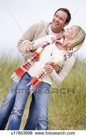 Stock Photo - Couple standing on beach smiling. Fotosearch