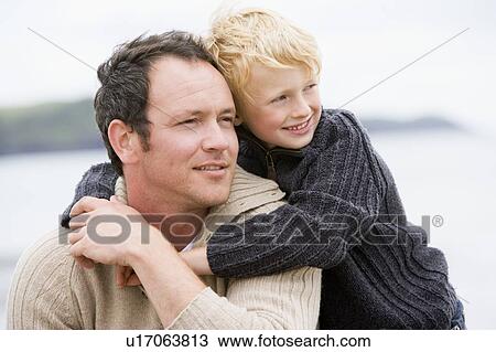 Stock Image - Father and son at beach smiling. Fotosearch