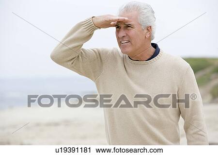 Man at the beach looking out with hand over eyes View Large Photo Image Stock Image - Man at the beach looking out with hand over eyes. Fotosearch