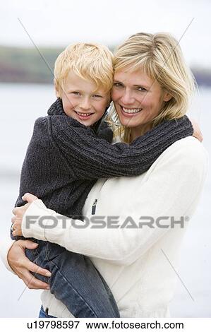 Stock Photo - Mother holding son at beach smiling. Fotosearch