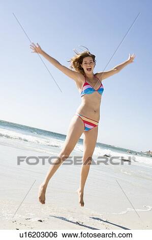 Woman in a two piece bathing suit jumping on a beach View Large Photo Image Stock Photograph - Woman in a two piece bathing suit jumping on a beach. Fotosearch
