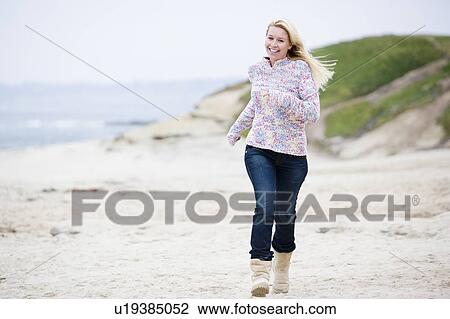 Stock Image - Woman running at beach smiling. Fotosearch