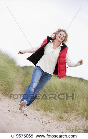 Stock Photography - Woman running at beach smiling. Fotosearch