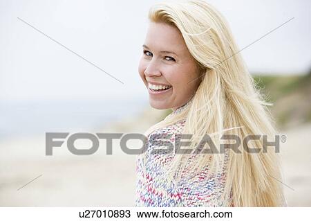 Stock Image - Woman standing at beach smiling. Fotosearch