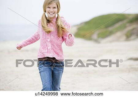 Stock Photo - Young girl running at beach smiling. Fotosearch