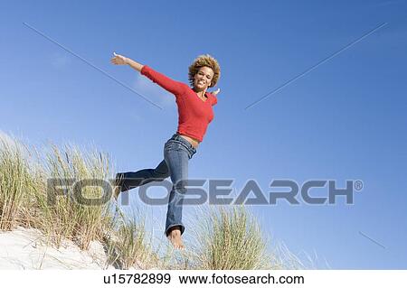 Young woman jumping on a sand hill View Large Photo Image Stock Photo - Young woman jumping on a sand hill. Fotosearch